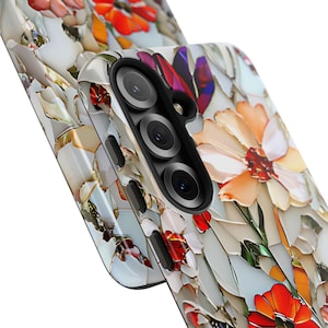 May include: A white phone case with a floral design. The case has a camera lens cutout and a white background with colorful flowers.