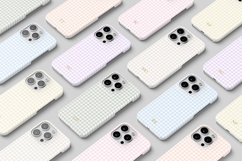 May include: A collection of pastel-colored phone cases arranged on a light gray surface. Each case features a gingham pattern in shades of pink, blue, green, and yellow. Some cases have gold initials. The cases are designed for a smartphone.