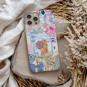 K&ouml;nnte beinhalten: Dekorative Handyh&uuml;lle mit einem Aquarelldesign. Die H&uuml;lle zeigt einen Golden Retriever mit Blumen, einen Leuchtturm sowie florale und Schleifen-Akzente. Die H&uuml;lle hat einen blau-wei&szlig;en Rand und den Text "How Lucky Are We".