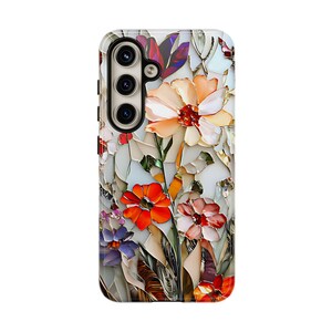 May include: A phone case with a colorful floral design. The flowers are made of different colored pieces of glass, creating a mosaic effect. The case is white with a camera cutout.