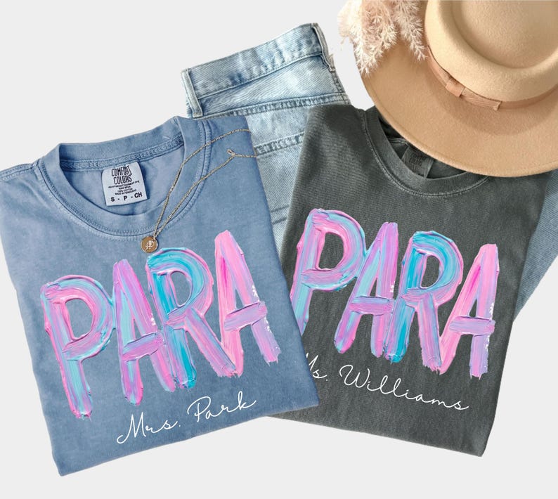 May include: Two t-shirts with the word "PARA" in a colorful, brushstroke design. One is light blue with "Mrs. Park" below, the other is gray with "Ms. Williams". A gold necklace, jeans, and a beige hat are also in the image.