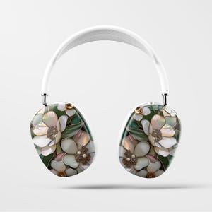 May include: White wireless headphones with a floral design featuring white, pink, and green flowers. The headphones have a white headband and white earcups.