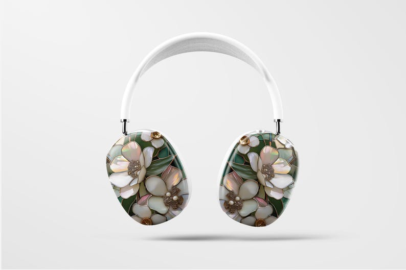 May include: White wireless headphones with a floral design featuring white, pink, and green flowers. The headphones have a white headband and white earcups.