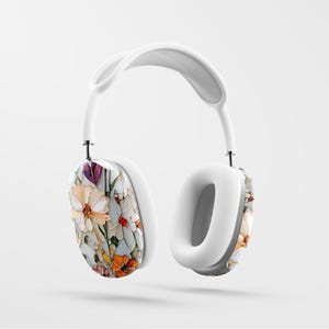 May include: White over-ear headphones with a floral pattern on the earcups. The pattern features a variety of flowers in shades of pink, orange, yellow, and purple.
