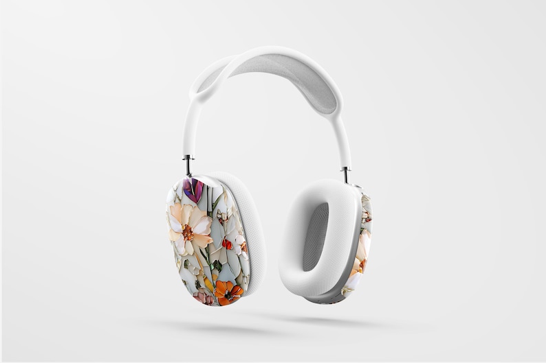 May include: White over-ear headphones with a floral pattern on the earcups. The pattern features a variety of flowers in shades of pink, orange, yellow, and purple.