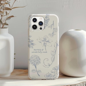 May include: A phone case with a floral design in blue and white. The case features various flower illustrations and the text "fearfully & wonderfully made. Psalm 139."