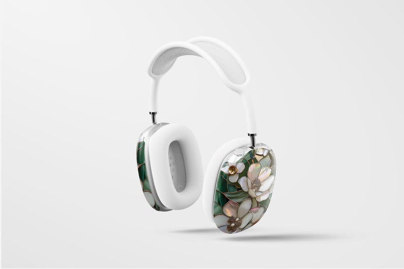 May include: White headphones with a floral design on one earcup. The design features green leaves, white flowers, and gold accents.