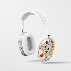 May include: White wireless headphones with a floral pattern on one earcup. The floral pattern features white, orange, and yellow flowers.