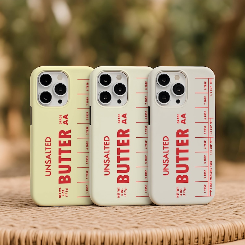 May include: Three phone cases in shades of yellow, cream, and white, each featuring the word "UNSALTED BUTTER" in red, with a measurement guide. The cases also display "NET WT. 4 OZ. (113g)" and "GRADE AA".