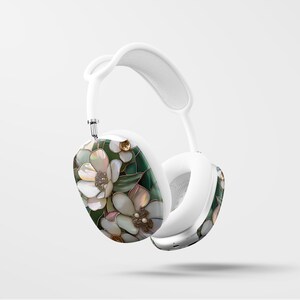 May include: White headphones with a floral design featuring white flowers and green leaves. The flowers have a pearl-like texture.