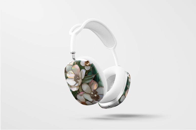 May include: White headphones with a floral design featuring white flowers and green leaves. The flowers have a pearl-like texture.