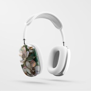 May include: White over-ear headphones with a floral design on one earcup. The design features white, green, and gold accents.