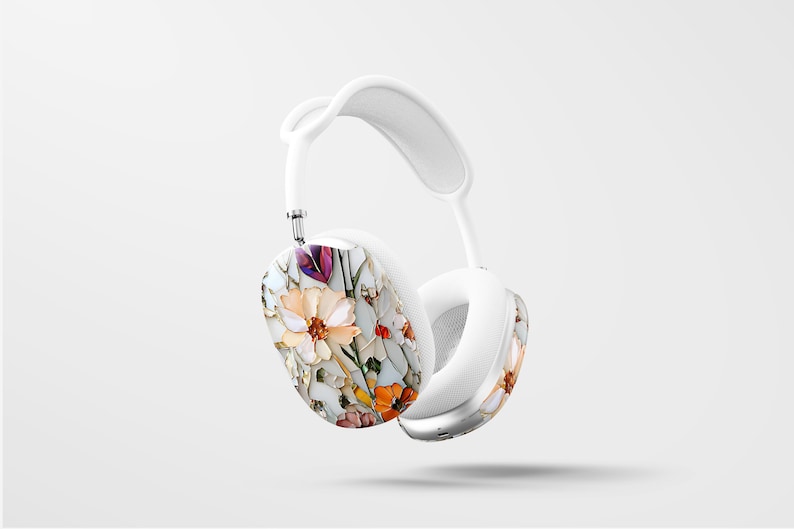May include: White wireless headphones with a floral design on the earcups. The design features a variety of flowers in shades of pink, orange, yellow, and purple.