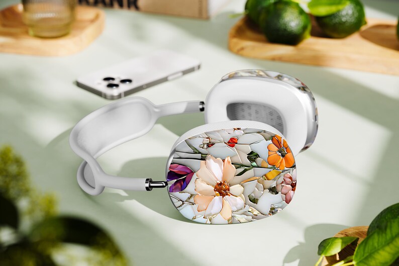 May include: White headphones with a floral design on the earcups. The design features a variety of flowers, including pink, purple, and orange, on a white background.
