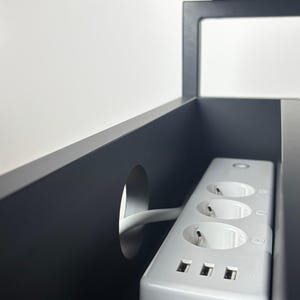 Puede incluir: Regleta blanca con tres enchufes est&aacute;ndar y tres puertos USB. La regleta est&aacute; montada dentro de un armario negro con un agujero para el cable.