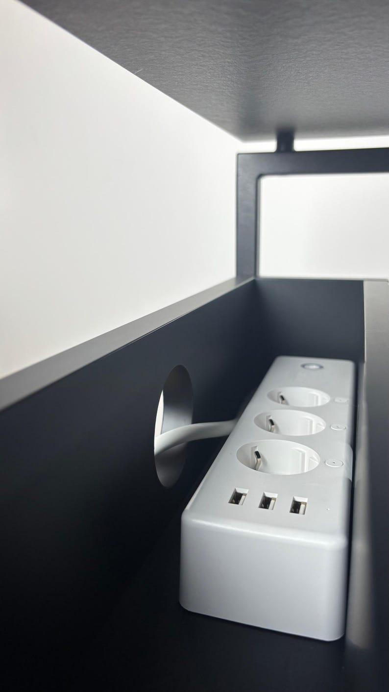 Puede incluir: Regleta blanca con tres enchufes est&aacute;ndar y tres puertos USB. La regleta est&aacute; montada dentro de un armario negro con un agujero para el cable.