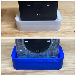 May include: Two 3D printed stands for an iPod. The stand on the top is white and the stand on the bottom is blue.