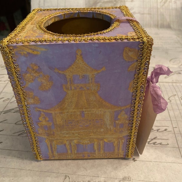 A one-of-a-kind, hand-crafted, tissue box cover decoupaged with an Asian-inspired, gold pagoda on a lavender backgroundprint.