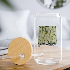 May include: A clear glass reusable water bottle with a bamboo lid and a straw. The bottle has a graphic of the state of New Mexico with the text "New Mexico" printed on it.