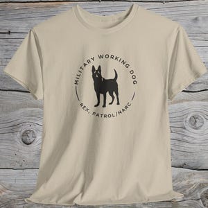 May include: A beige t-shirt with a black circle graphic featuring a silhouette of a dog and the text "Military Working Dog Rex, Patrol/Narc".