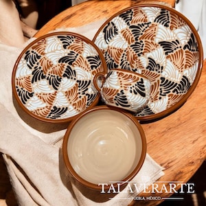 May include: A ceramic tableware set featuring a large plate, a smaller plate, a bowl, and a mug. The set has a brown rim and a repeating pattern of black, white, and brown fan-like shapes. The text "TALAVERARTE - PUEBLA, MÉXICO" is at the bottom.