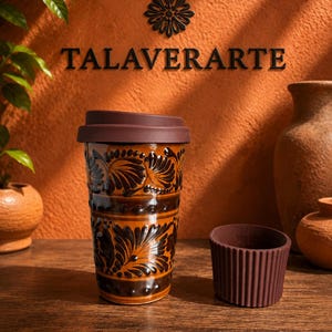 May include: A ceramic travel mug with a glossy orange and dark brown floral pattern, featuring a dark brown silicone lid. Beside it sits a small, dark brown, ribbed silicone cup sleeve. The word TALAVERARTE is displayed in black letters above.