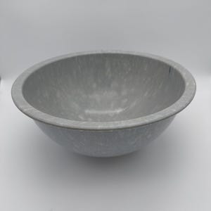 May include: A round, medium-sized mixing bowl with a smooth, matte finish. The bowl features a speckled, mottled pattern in shades of light gray and white, creating a textured appearance across the entire interior and exterior surface.