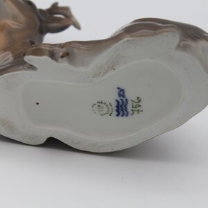 May include: The bottom of a porcelain figurine of a deer. The figurine is brown and white and has a blue and white mark on the bottom that reads "1516".
