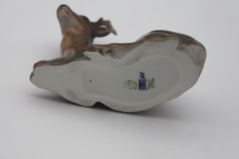 May include: A brown porcelain figurine of a deer with a white underside and a blue and white mark on the bottom that reads "1572".