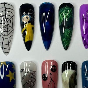 May include: A collection of ten long, pointed false nails, each with a unique design. Designs include a spiderweb, a cartoon character in a yellow coat, abstract blue and white swirls, a green spiderweb, and purple patterns. The nails are painted in various colours.