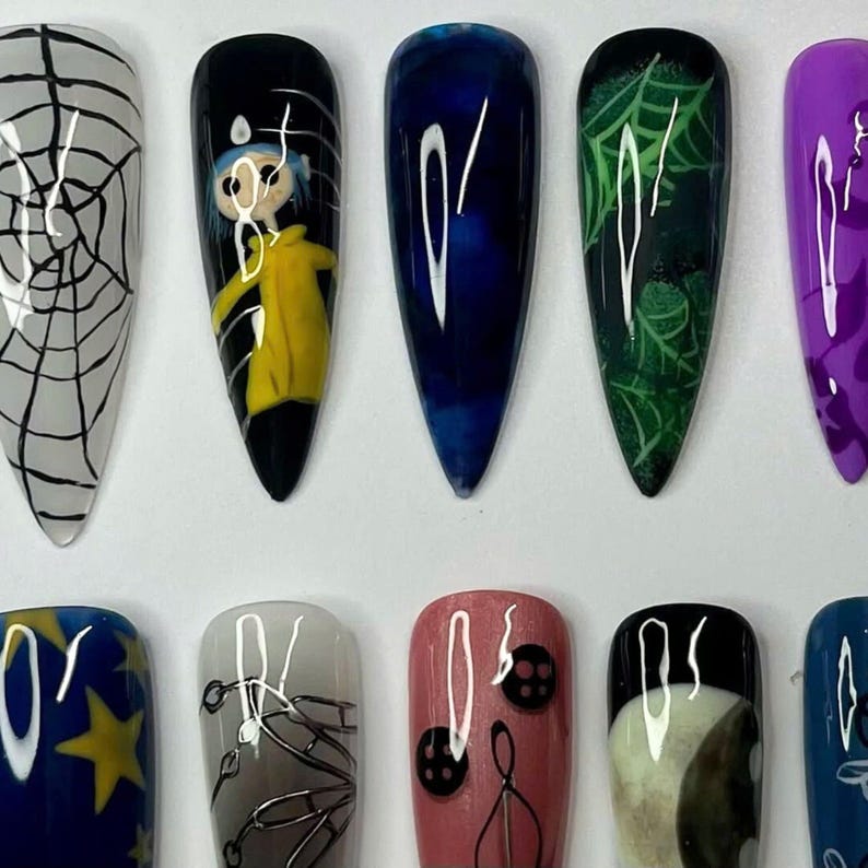 May include: A collection of ten long, pointed false nails, each with a unique design. Designs include a spiderweb, a cartoon character in a yellow coat, abstract blue and white swirls, a green spiderweb, and purple patterns. The nails are painted in various colours.