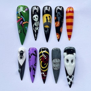 May include: A collection of ten long, pointed acrylic nails featuring Halloween designs. The designs include a skeleton, ghosts, pumpkins, and the text "Worm's Wort". The colour palette includes black, white, orange, green, yellow, and purple.