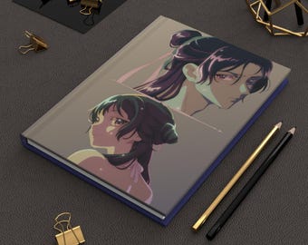 May include: A blue notebook with a colorful illustration of two anime characters. The characters have long dark hair and are drawn in a stylized fashion. The notebook is on a gray surface with two pencils.