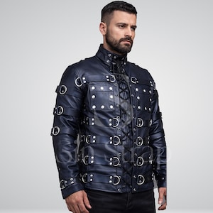 Puede incluir: Chaqueta de cuero azul marino con múltiples anillos y correas de metal plateado. La chaqueta tiene cuello alto, cierre frontal con cordones y múltiples bolsillos. El diseño está detallado con tachuelas y anillas en D plateadas.