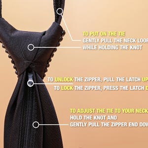 May include: A black necktie featuring a zipper mechanism and instructional text. The text reads: TO PUT ON THE TIE GENTLY PULL THE NECK LOOP UP WHILE HOLDING THE KNOT, TO UNLOCK THE ZIPPER PULL THE LATCH UP, TO LOCK THE ZIPPER PRESS THE LATCH DOWN, TO ADJUST THE TIE TO YOUR NECK SIZE HOLD THE KNOT AND GENTLY PULL THE ZIPPER END DOWN.