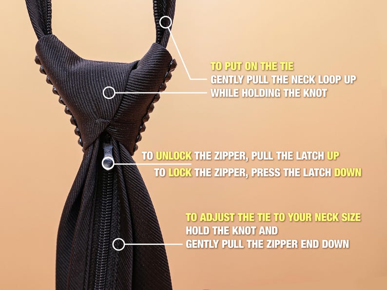 May include: A black necktie featuring a zipper mechanism and instructional text. The text reads: TO PUT ON THE TIE GENTLY PULL THE NECK LOOP UP WHILE HOLDING THE KNOT, TO UNLOCK THE ZIPPER PULL THE LATCH UP, TO LOCK THE ZIPPER PRESS THE LATCH DOWN, TO ADJUST THE TIE TO YOUR NECK SIZE HOLD THE KNOT AND GENTLY PULL THE ZIPPER END DOWN.