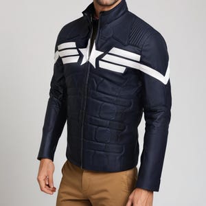 May include: Navy blue jacket with white star and stripe design. The jacket has a quilted pattern on the front and a stand-up collar. The sleeves are long and the jacket is zipped up. The jacket is worn with khaki pants.