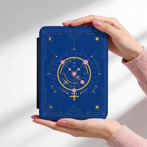 Könnte beinhalten: Eine blaue, rechteckige Hülle mit einem himmlischen Design in Gold und Rosa. Das Design umfasst geometrische Formen, einen Halbmond, eine Sonne und ein Venus-Symbol. Die Hülle wird von zwei Händen gehalten.