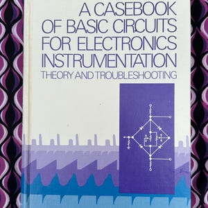 May include: A white book with a purple and blue design on the cover. The title is "A Casebook of Basic Circuits for Electronics Instrumentation: Theory and Troubleshooting" by George C. Stanley, Jr. Editor.