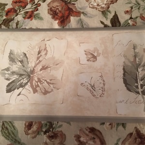 May include: Beige wallpaper border with a repeating pattern of leaves and butterflies. The text "Isn't that's so" is printed on the border.