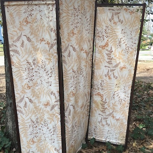 May include: A three-panel room divider with a brown wood frame and a white fabric panel with a brown fern and butterfly pattern.