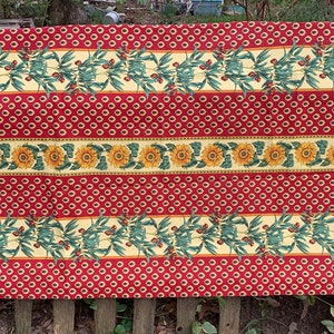 May include: Red and yellow striped tablecloth with a sunflower and olive branch pattern.