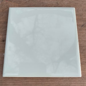 May include: A plain white ceramic tile with a glossy finish.
