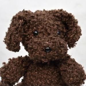 May include: A brown plush toy dog with curly fur. The dog has black button eyes and a black nose. The toy is made of a soft, textured material and has floppy ears. The dog's fur is a rich, chocolate brown color.