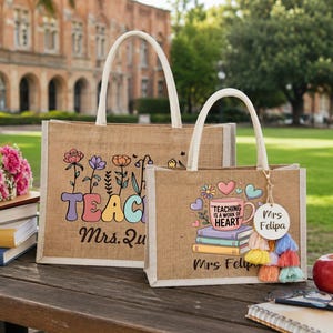 May include: Two rectangular jute tote bags with white handles. The larger bag features colorful floral graphics, the word TEACH, and the name Mrs. Qu. The smaller bag displays a mug with the text TEACHING IS A WORK OF HEART, books, and Mrs. Felipa.