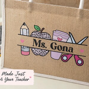 May include: A tan jute tote bag with white rope handles featuring a graphic print of a pencil, a leopard print apple, a coffee cup, and scissors. A horizontal banner across the center displays the black text Ms. Gona with small pink hearts.