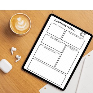 May include: A digital tablet with the text "AFFIRMATION PROMPTS" and prompts for self-reflection. A cup of coffee with latte art, wireless earbuds, and a charging case are on a wooden surface.