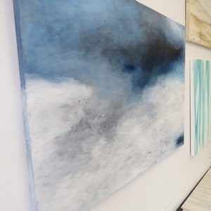 Op de afbeelding: Abstract schilderij op canvas in tinten van blauw, grijs en wit. Het schilderij heeft een textuur en een moderne stijl.