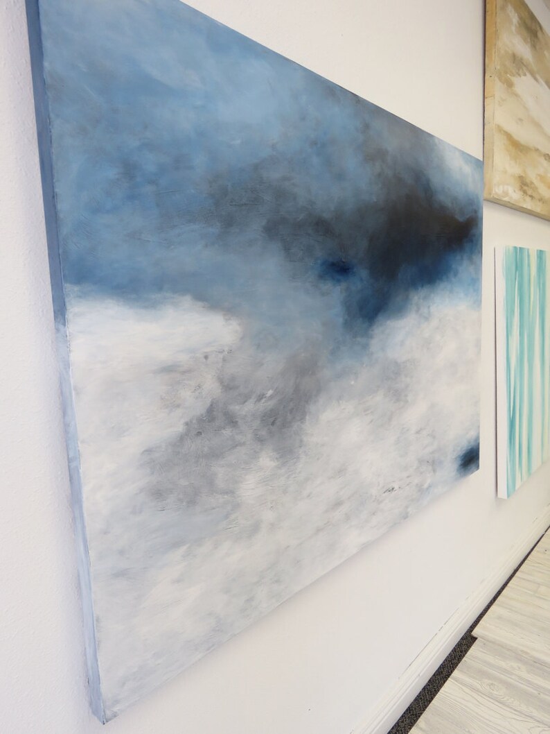 Op de afbeelding: Abstract schilderij op canvas in tinten van blauw, grijs en wit. Het schilderij heeft een textuur en een moderne stijl.