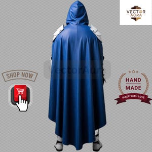 Puede incluir: Capa azul con capucha y hombreras blancas. La vista trasera muestra el dise&ntilde;o de la capa y la etiqueta "Hand Made". La capa es parte de un disfraz o atuendo de cosplay.